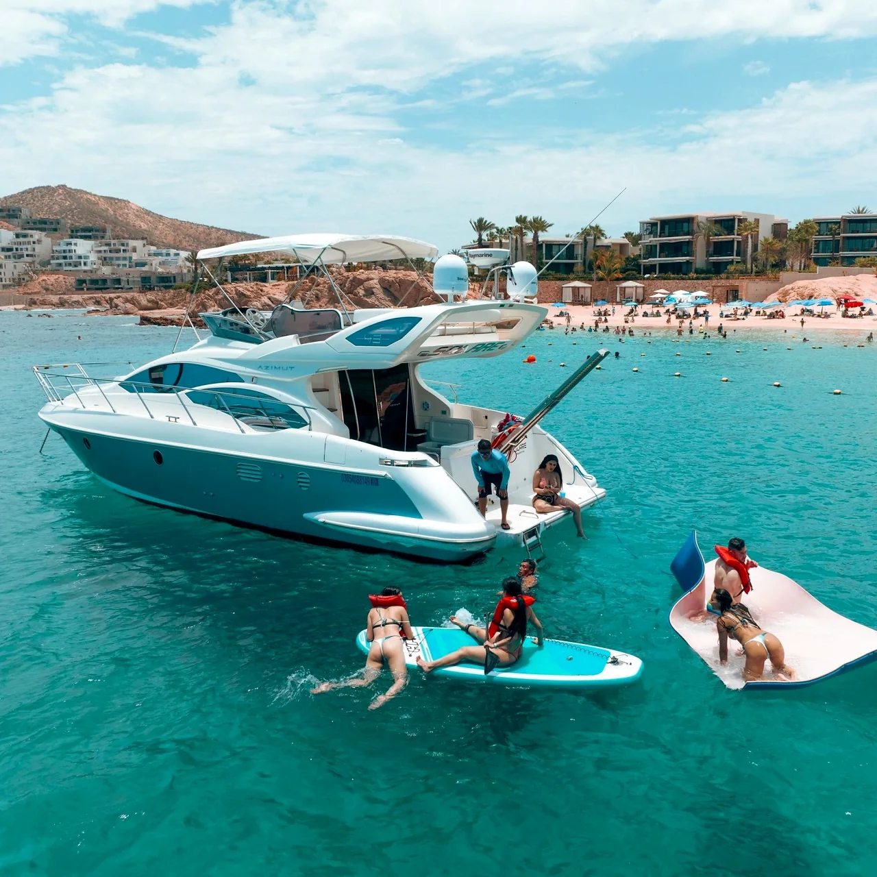 Yate y personas practicando paddleboard cerca de la costa