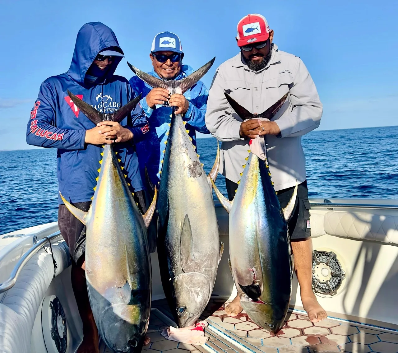 Pescadores sosteniendo atunes en una embarcación de pesca Pescadores sosteniendo atunes en una embarcación de pesca